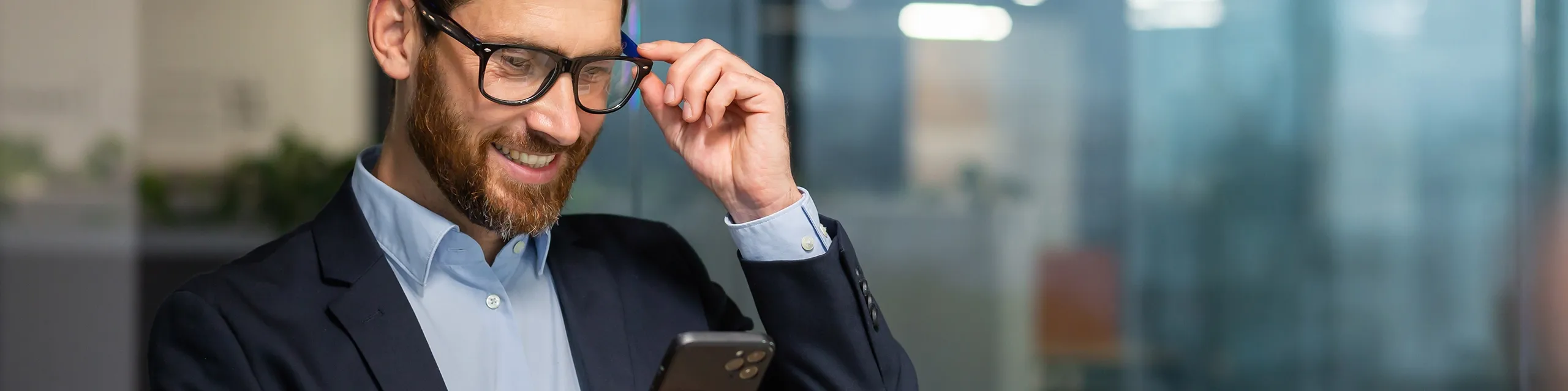 Mann checkt sein Handy im gläsernen Büro