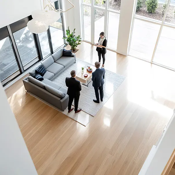 mmobilienmakler zeigt modernes Wohnzimmer mit großer Fensterfront aus Vogelperspektive fotografiert